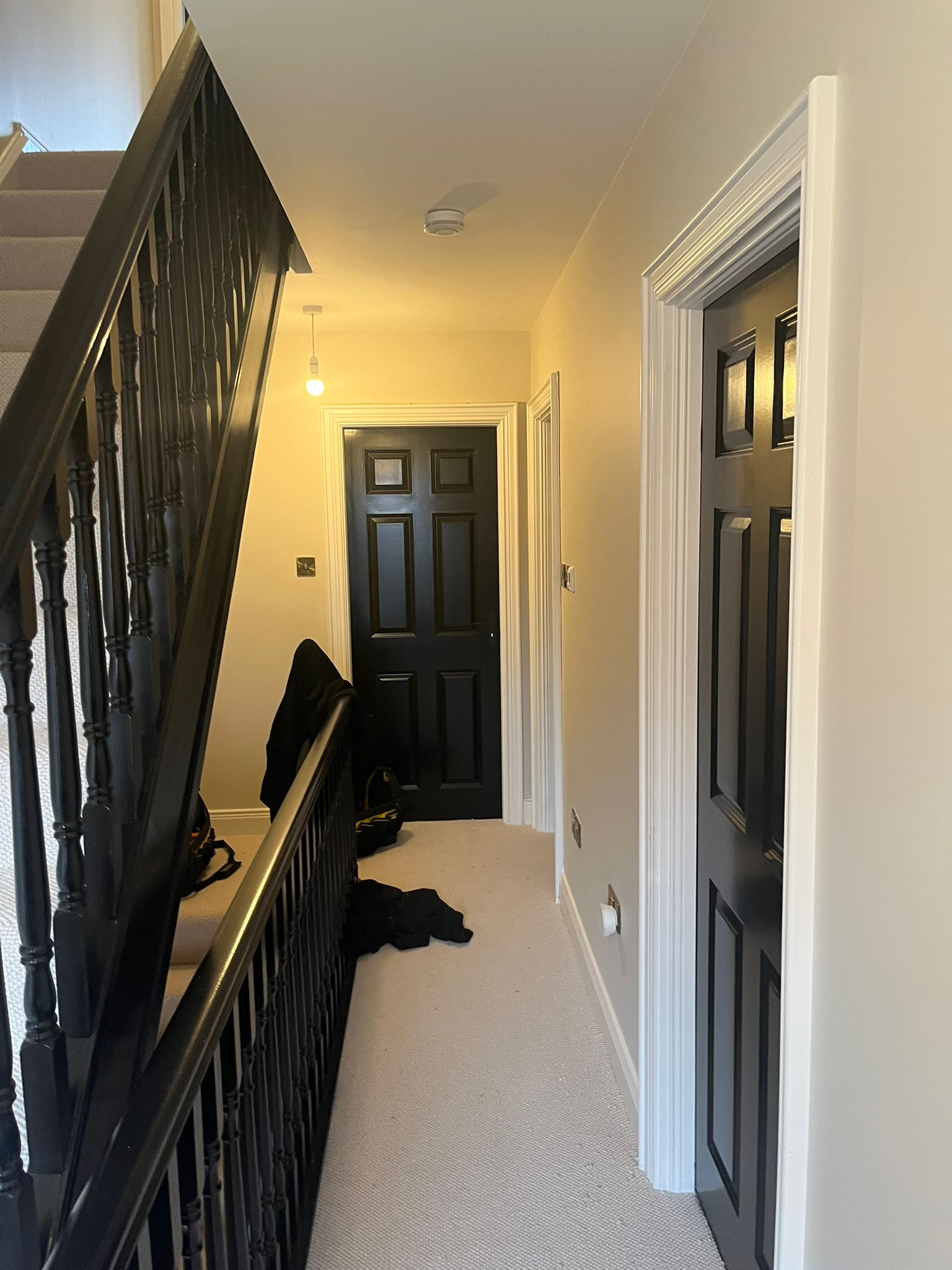 Landing hallway with black painted panelled doors, balustrade and carpet runner