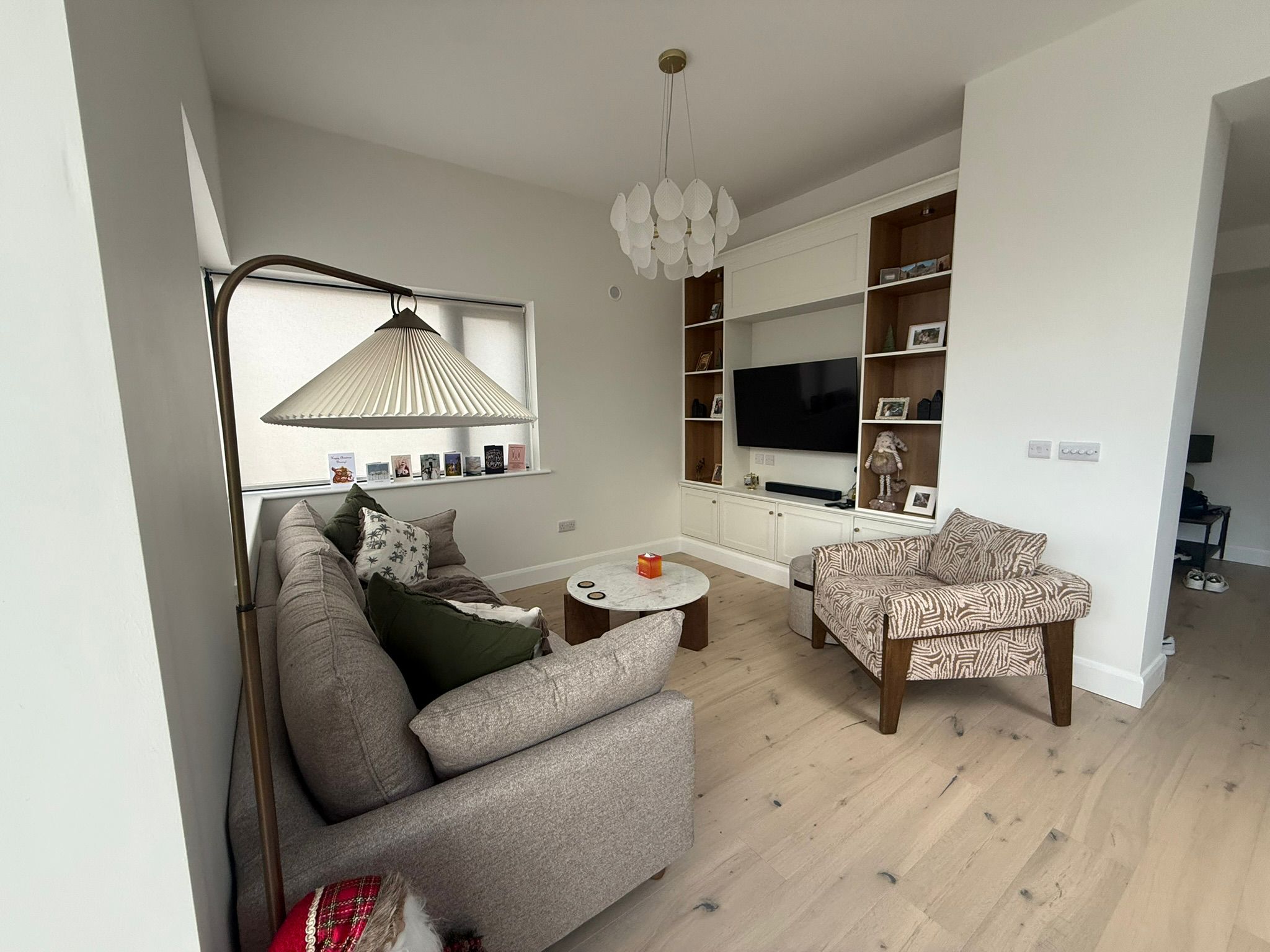Living room with white built-in shelving, TV unit and grey sofa