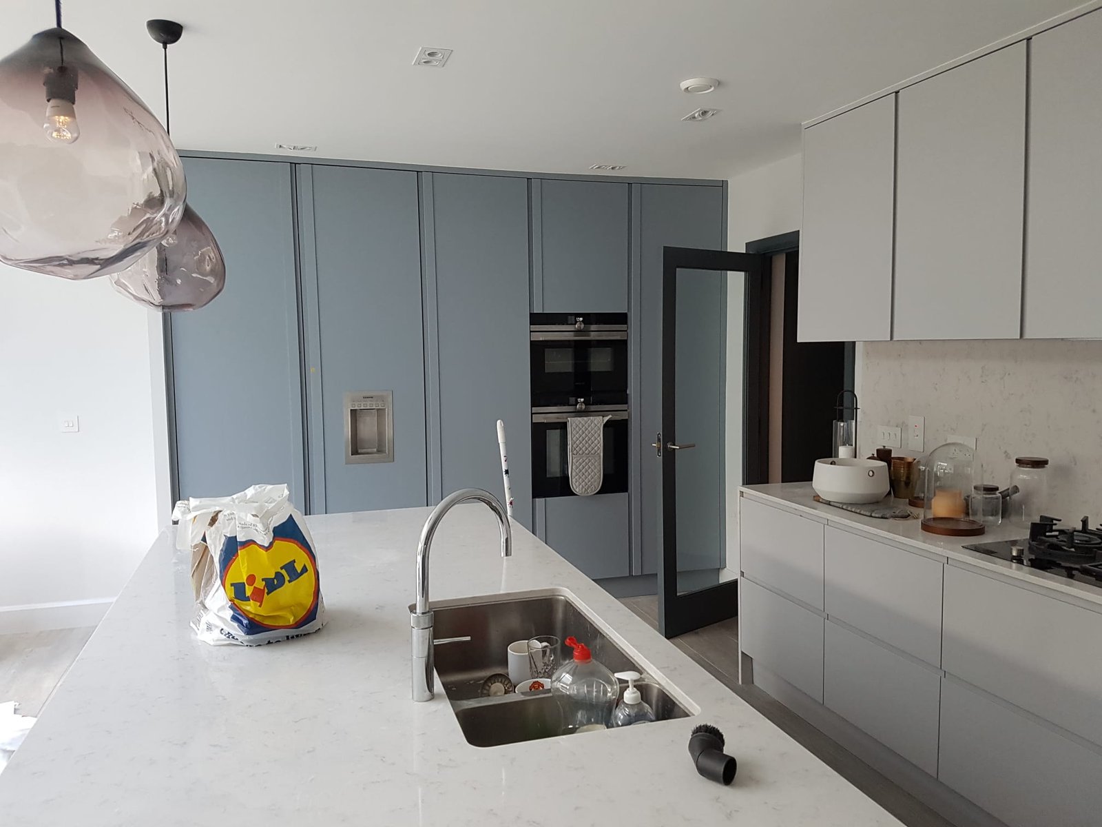 Blue-grey shaker kitchen with marble island and smoked glass pendants