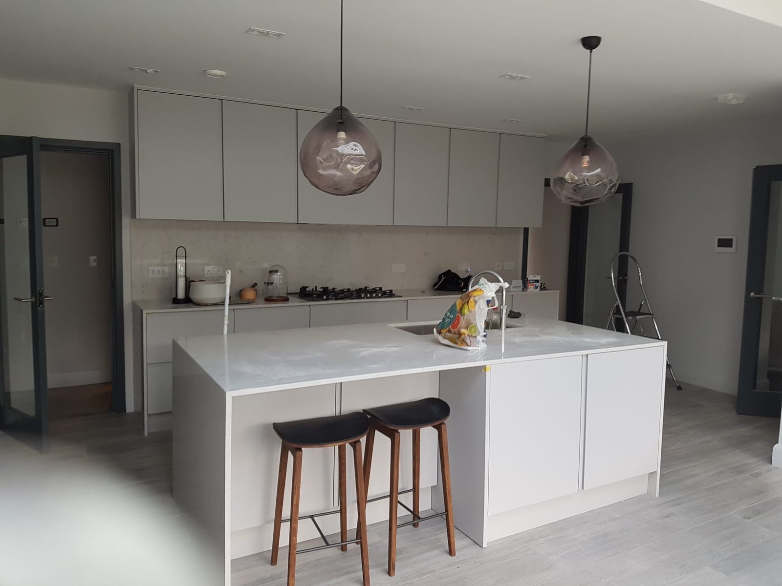 Modern grey handleless kitchen with large marble island and bar stools