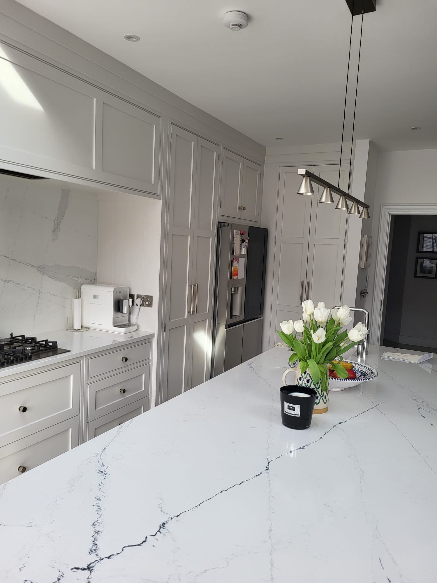 Grey shaker kitchen with marble countertop, American fridge and pendant rail light